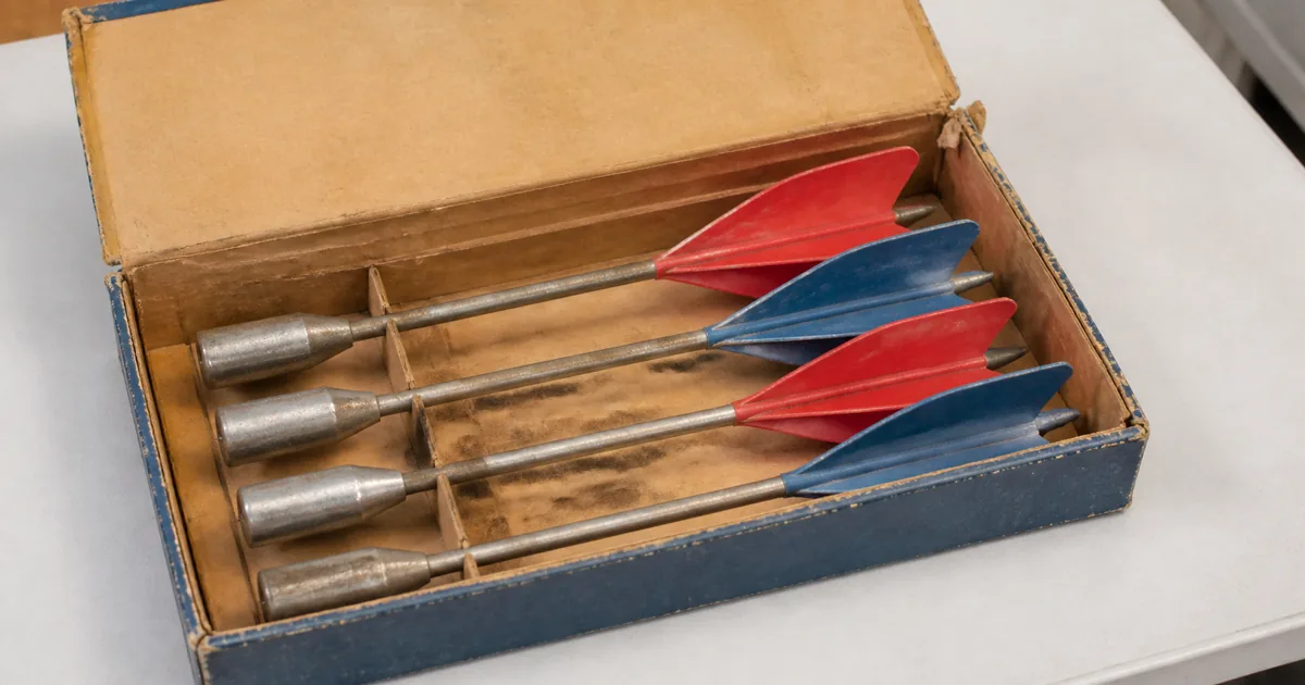 Vintage lawn darts and target rings arranged beside their original-style box