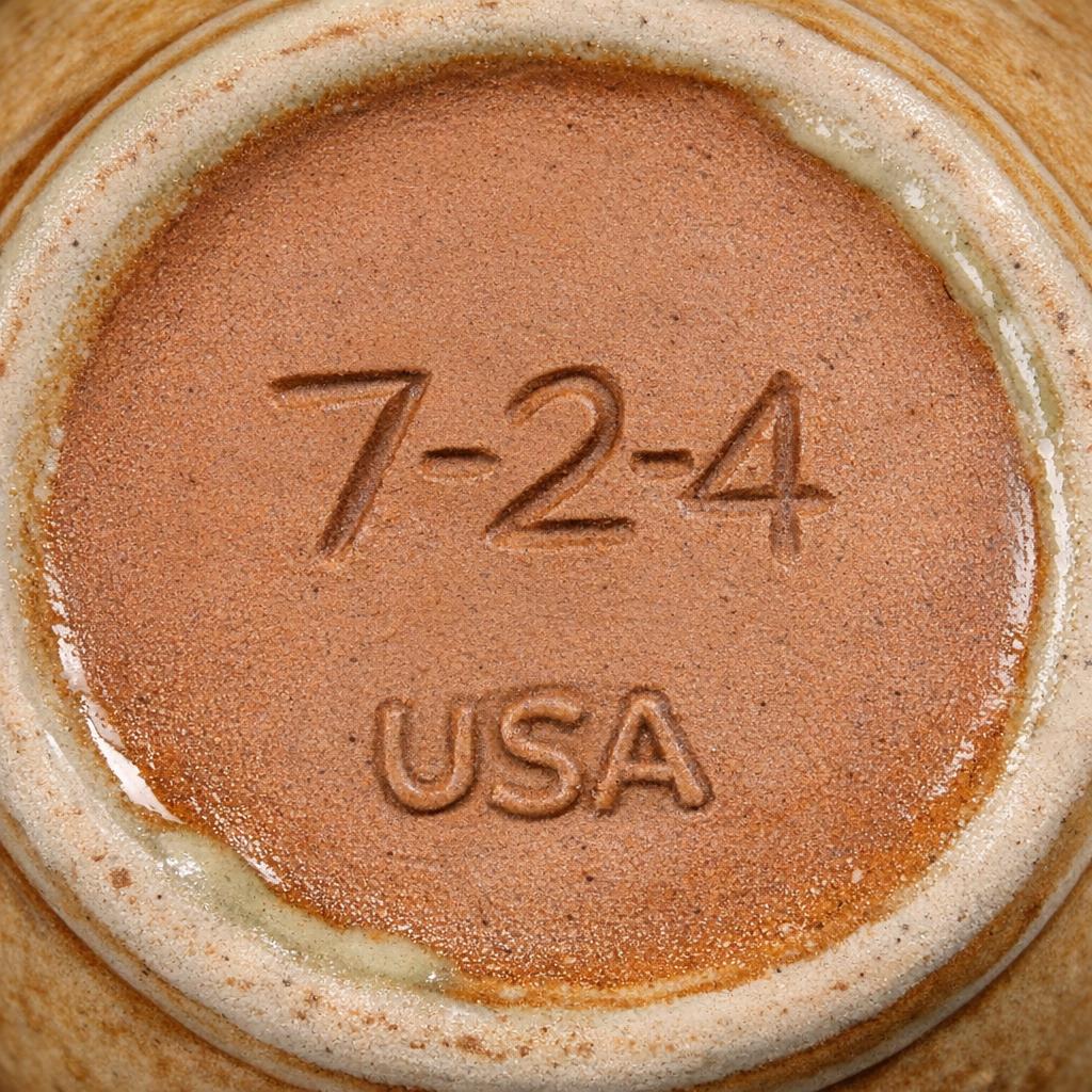 Bottom of a McCoy pottery piece showing both the USA mark and an incised shape form number, clear focus on the number